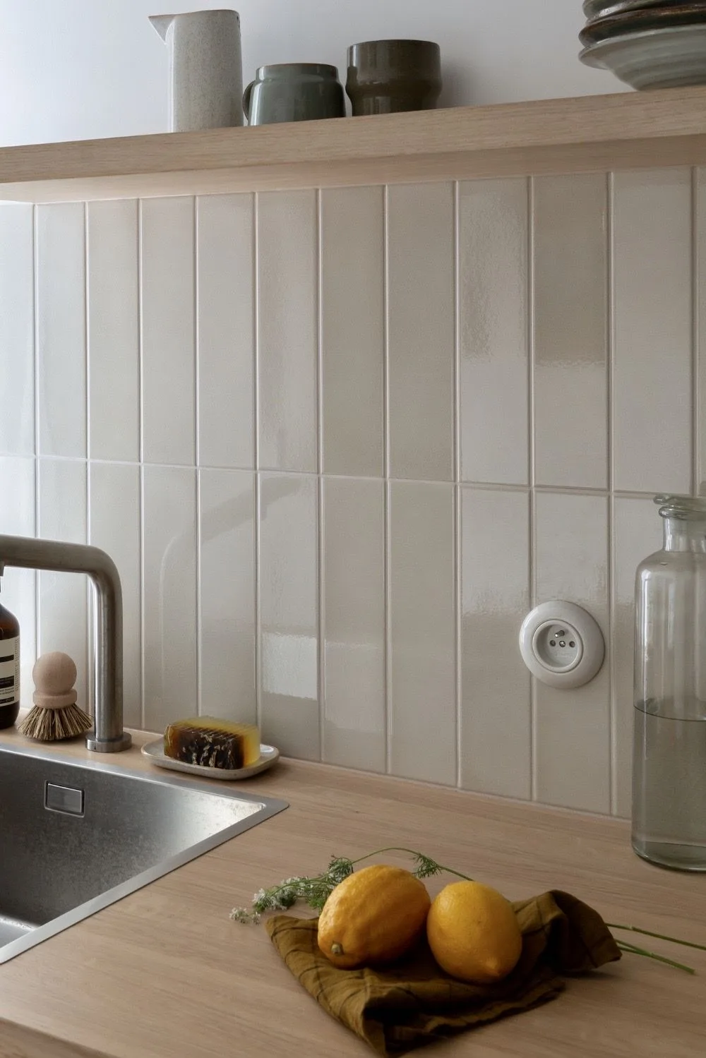 Warm beige zellige tile shower with brushed gold rain head and glass panel enclosure