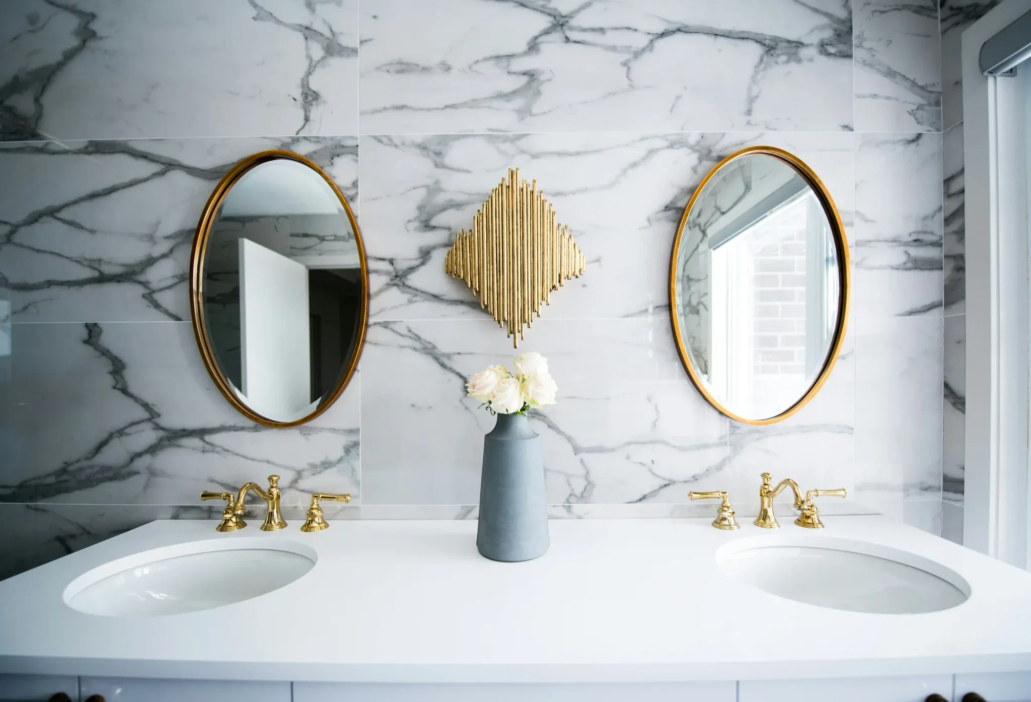 Luxury bathroom double sink vanity with white marble tile wall and brushed gold faucets